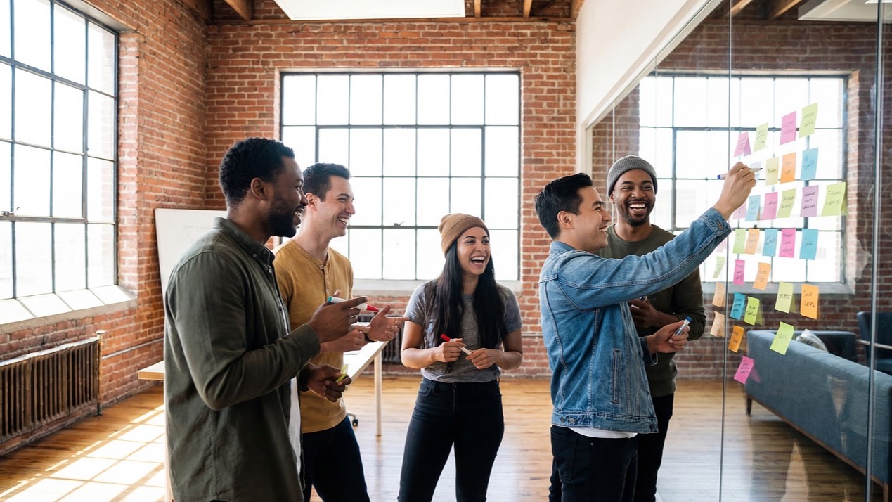 A team plans together on a glass wall covered in sticky notes