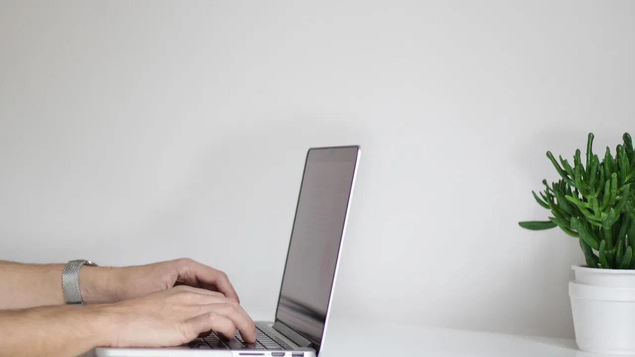 Hands typing on a laptop at a white desk, the daily work of keeping business data safe.