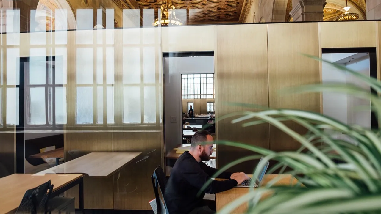 A man works on a laptop in a glass-walled office, where business data is handled every day.