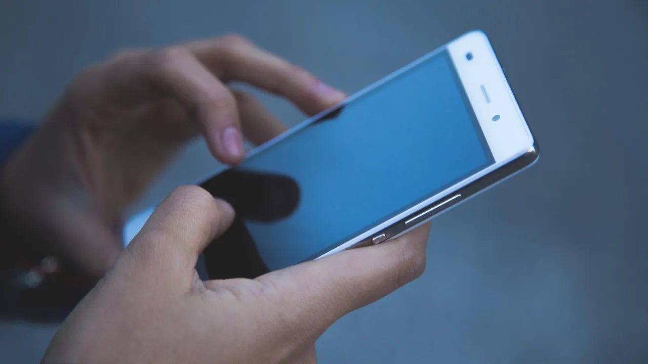 Close-up of hands holding and tapping a smartphone, the way most visitors reach a landing page.