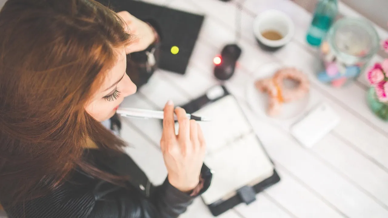 A business owner plans an app idea in a notebook at a desk before briefing a developer