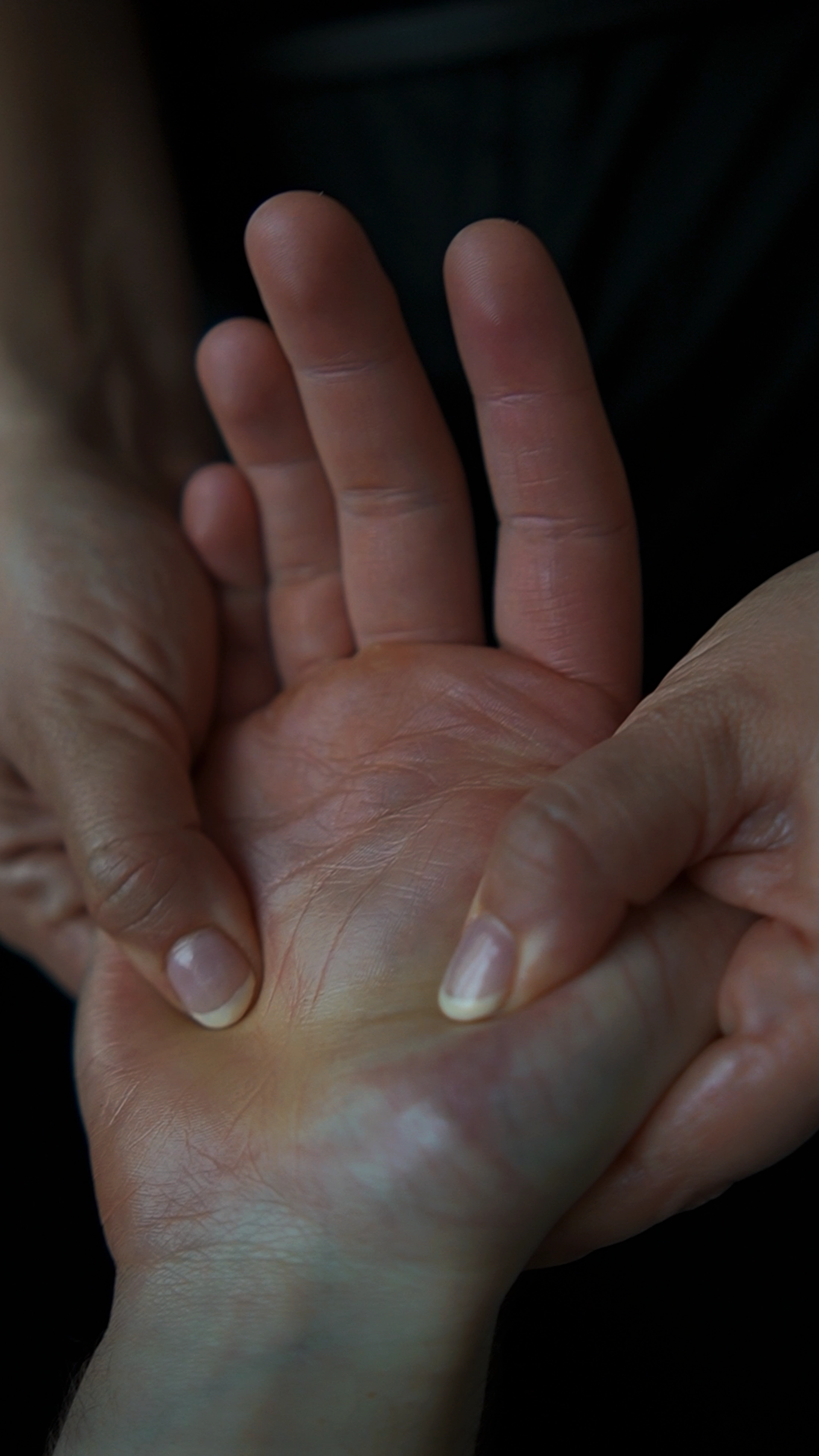 Close-up of hands applying pressure on the palm of another hand.