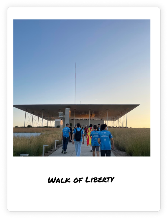 Polaroid photo of Team North Macedonia walking toward a modern architectural structure during the First Global Challenge 2024. The team is dressed in blue shirts, carrying the Macedonian flag, symbolizing their participation in the global robotics competition.