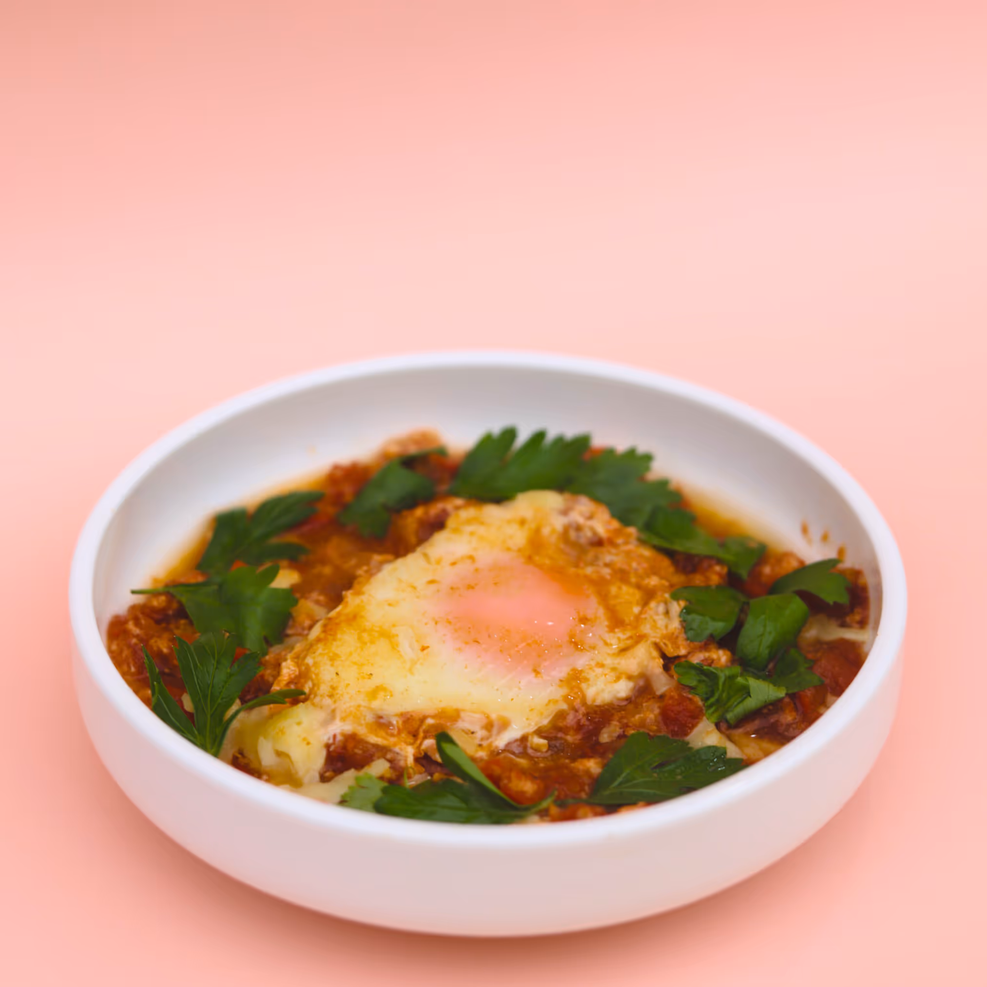 a plate of Shakshouka with pink background
