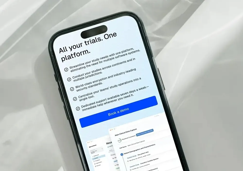 Smartphone zeigt eine Plattform zur Studienverwaltung mit Funktionen wie Verschlüsselung, zentrale Verwaltung und Support, inklusive Schaltfläche 'Demo buchen'.