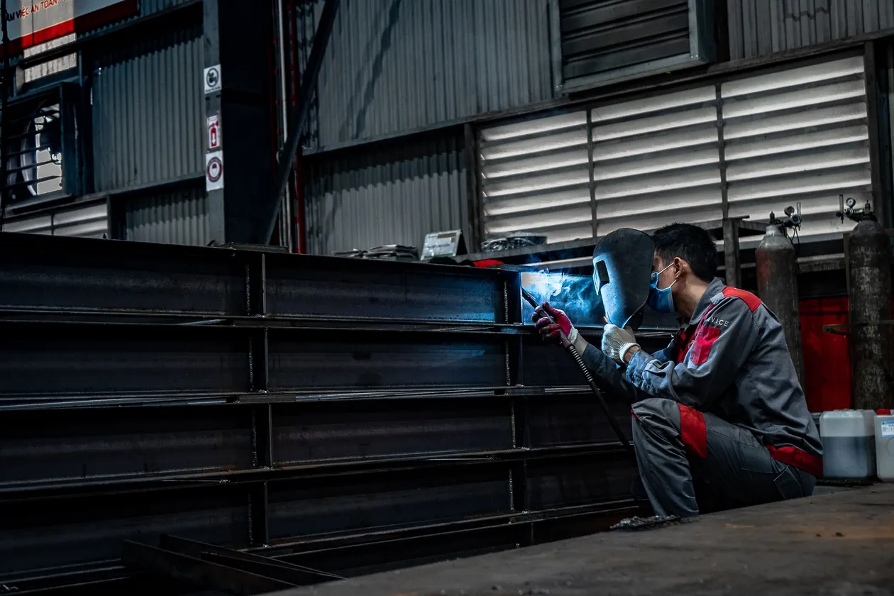 Digital Marketing Agency Tullamarine: a steel fabricator welding structural steel beams in a workshop, the kind of local manufacturing business we help