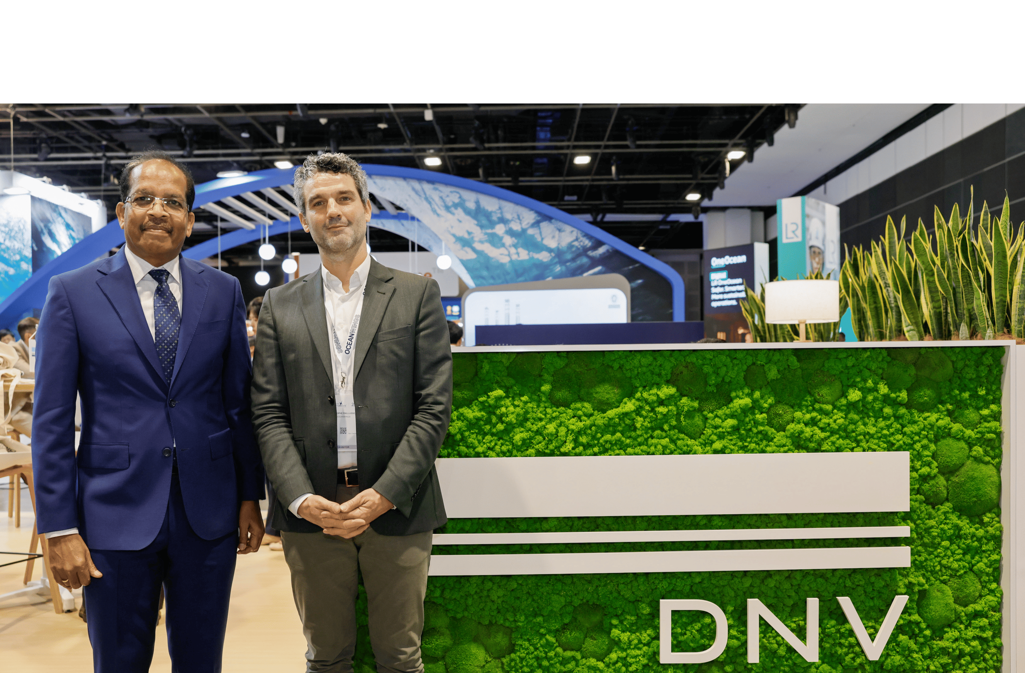 Two men, from OceanWings and from DNV, stand at Singapore Maritime Week 2026 in front of a DNV board.