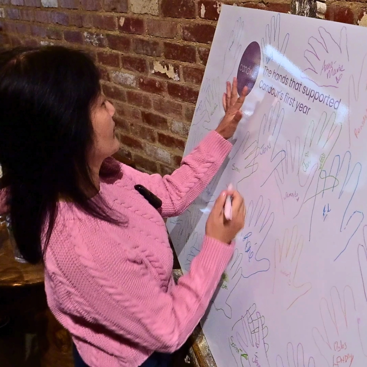 Guests tracing their hands on the Candour Champions board