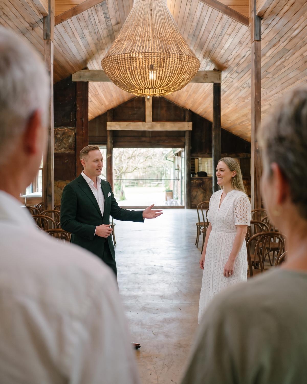 Simon and Sameiko showing a family through a timber barn venue, gesturing toward the space