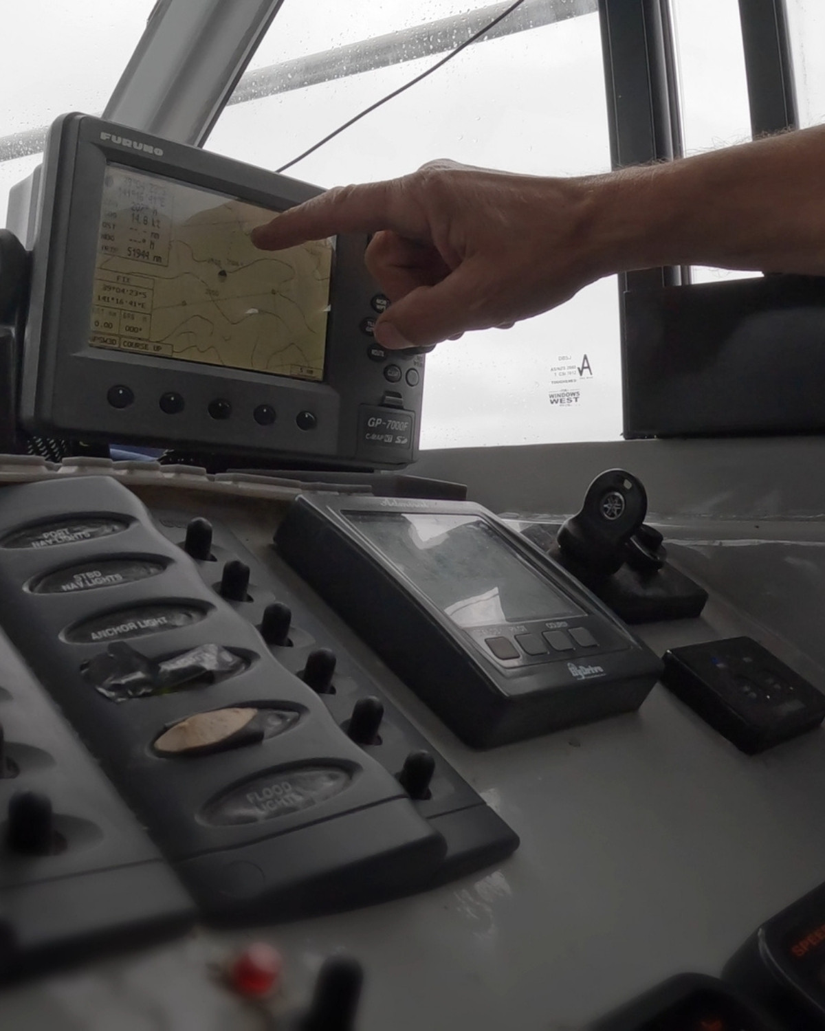 A hand at the vessel's chart plotter, finding the position on the open ocean