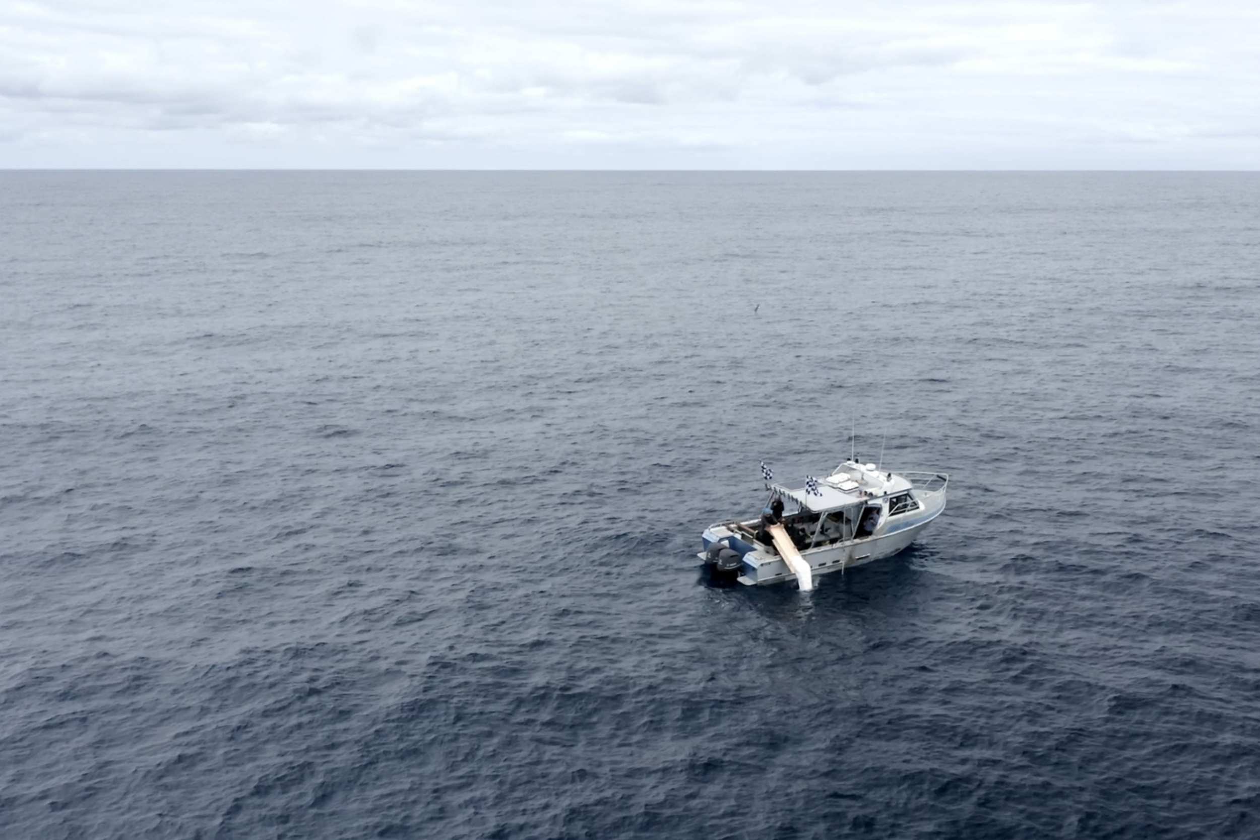 A small boat alone on open water offshore, a farewell at sea