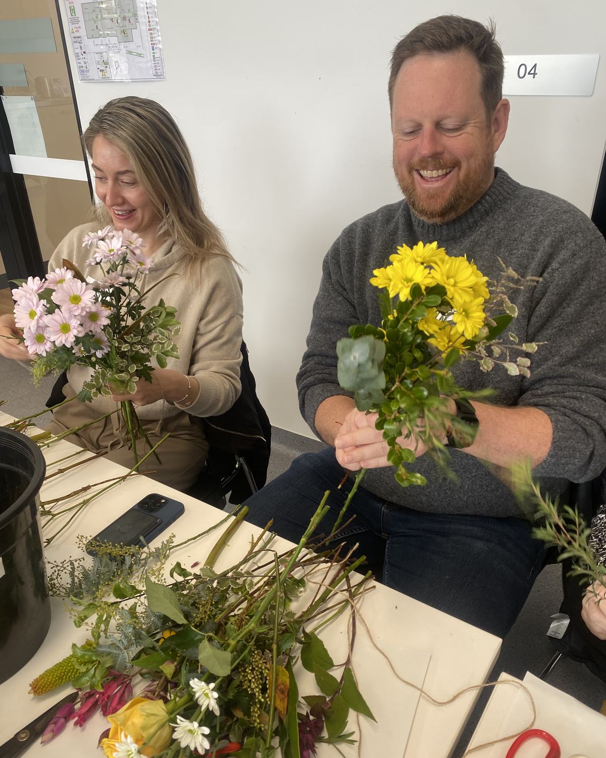 Two guests laugh as they hand-tie posies at our flower workshop with Val from The Bloom Room