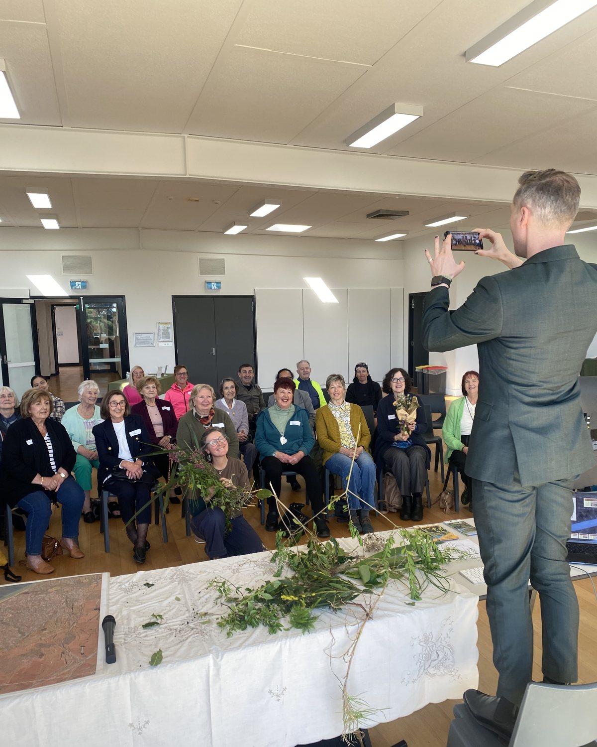 Simon stands on a chair to photograph a room full of smiling guests at Candour Connects