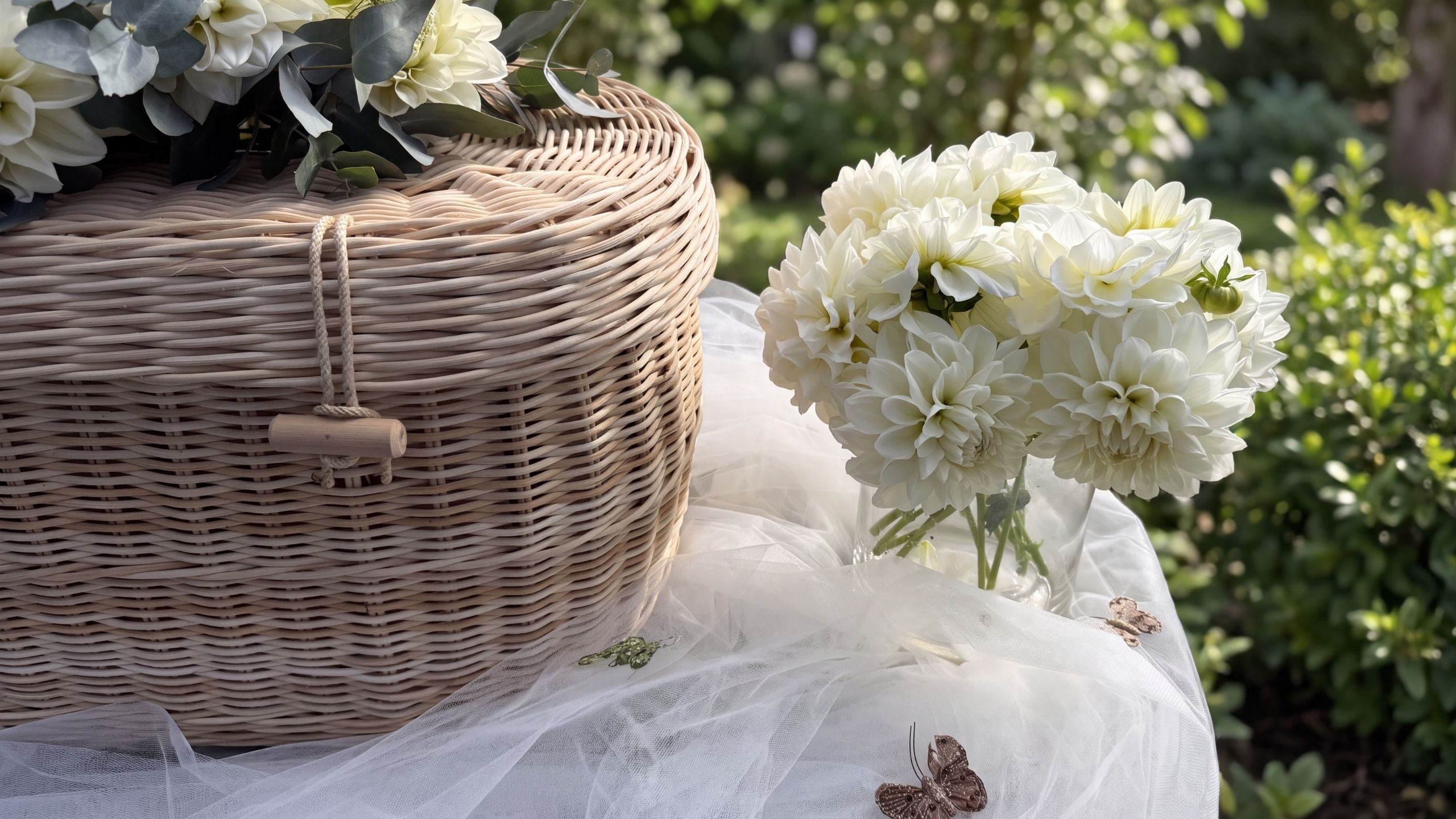 A garden in soft focus behind a woven casket and white dahlias