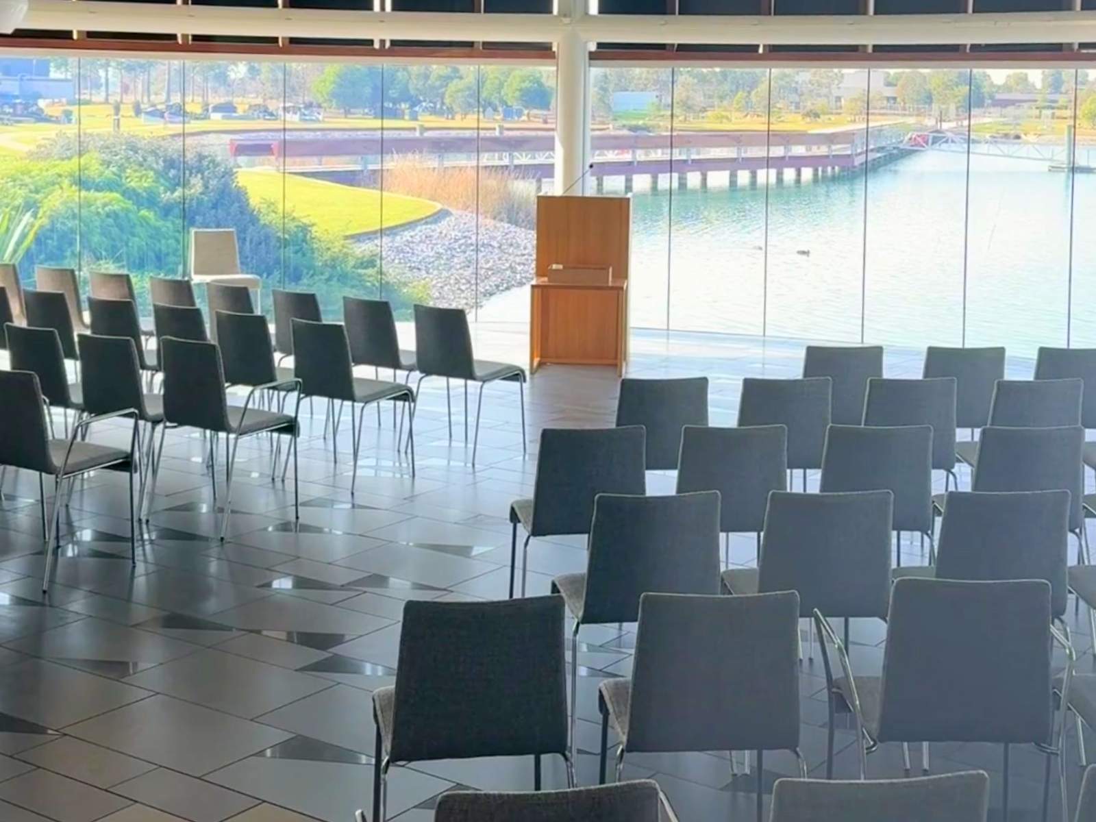 Inside of Sanctuary Chapel, empty chairs arranged looking through glass windows to the lake