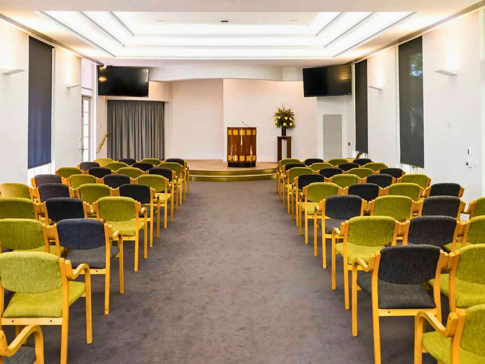 Inside Chapel of Repose at Altona Memorial Park showing green and black fabric chairs with wooden arms and legs