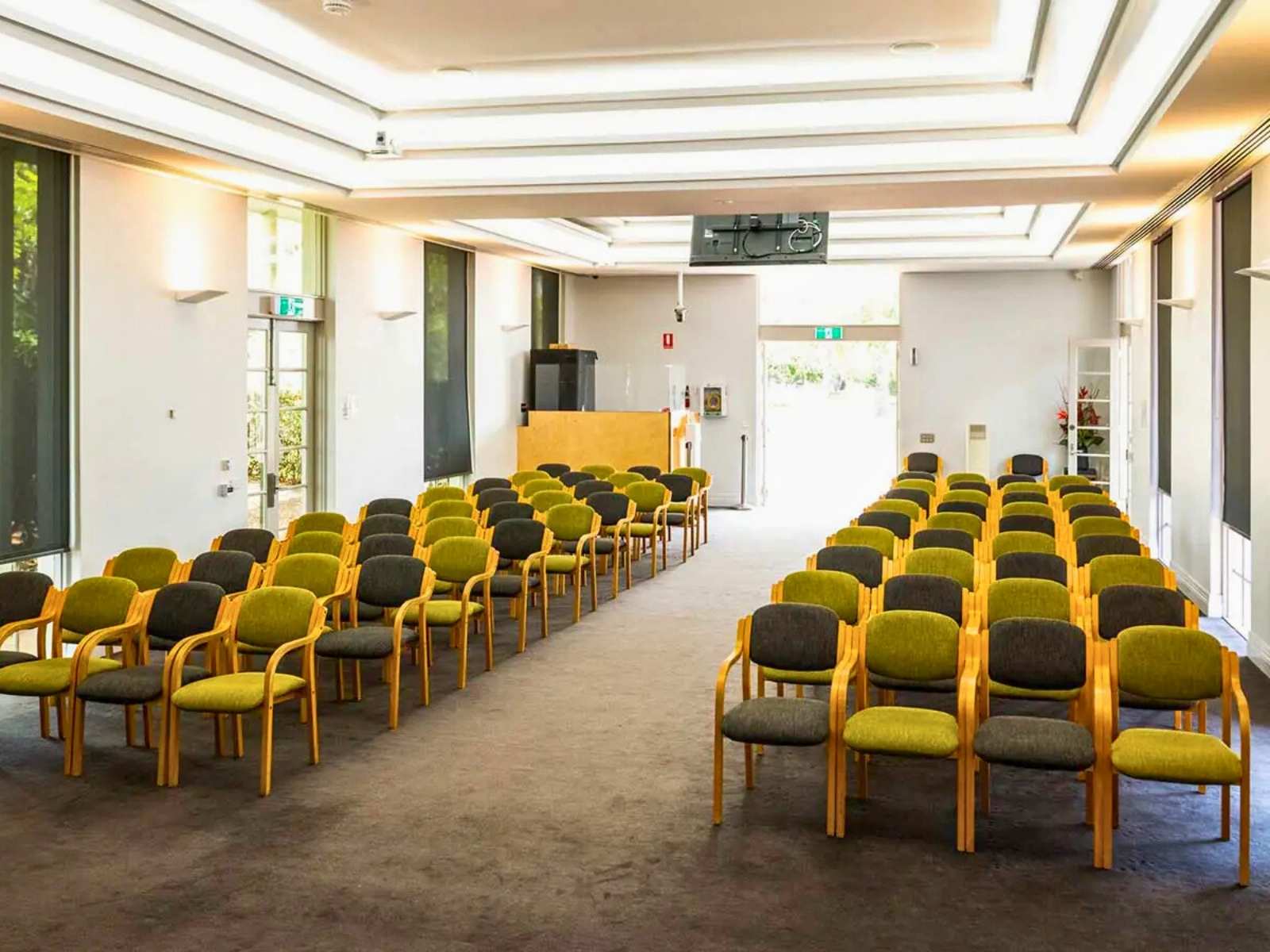 Inside Chapel of Repose at Altona Memorial Park showing view looking back at empty green and black chairs. 