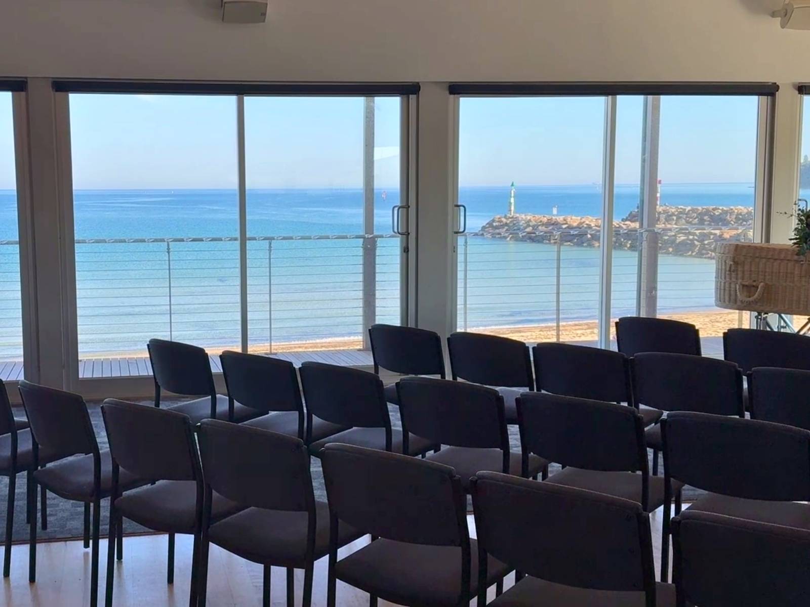 View from behind the seating area, showing rows of chairs facing windows with uninterrupted views of the tranquil ocean and sandy beach below.