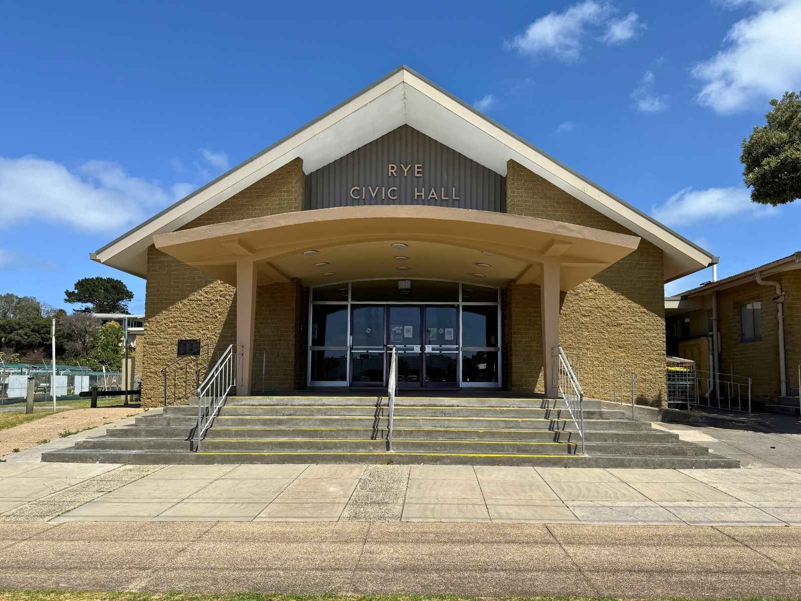 A centred image of Rye Civic Hall’s main entrance with wide concrete stairs, metal railings, and the venue’s name clearly displayed above the canopy.