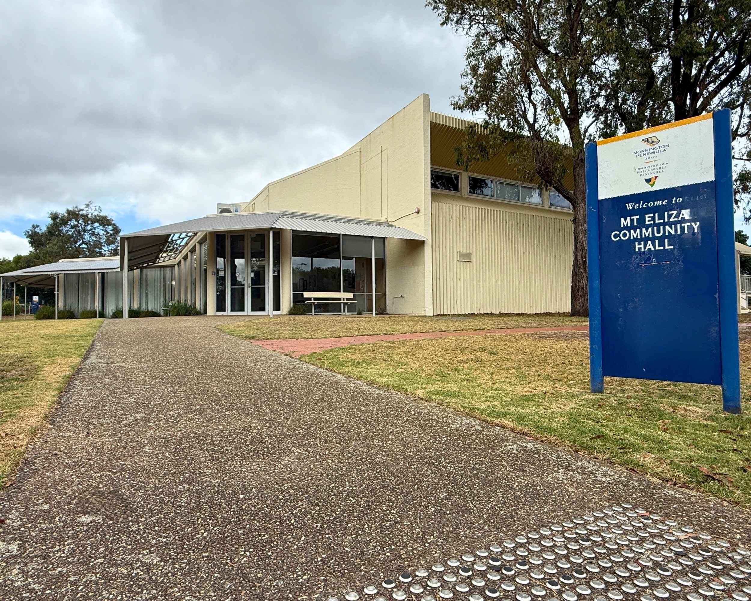 Exterior of Mount Eliza Community Hall with blue signage and clear pedestrian pathway leading to the entrance.