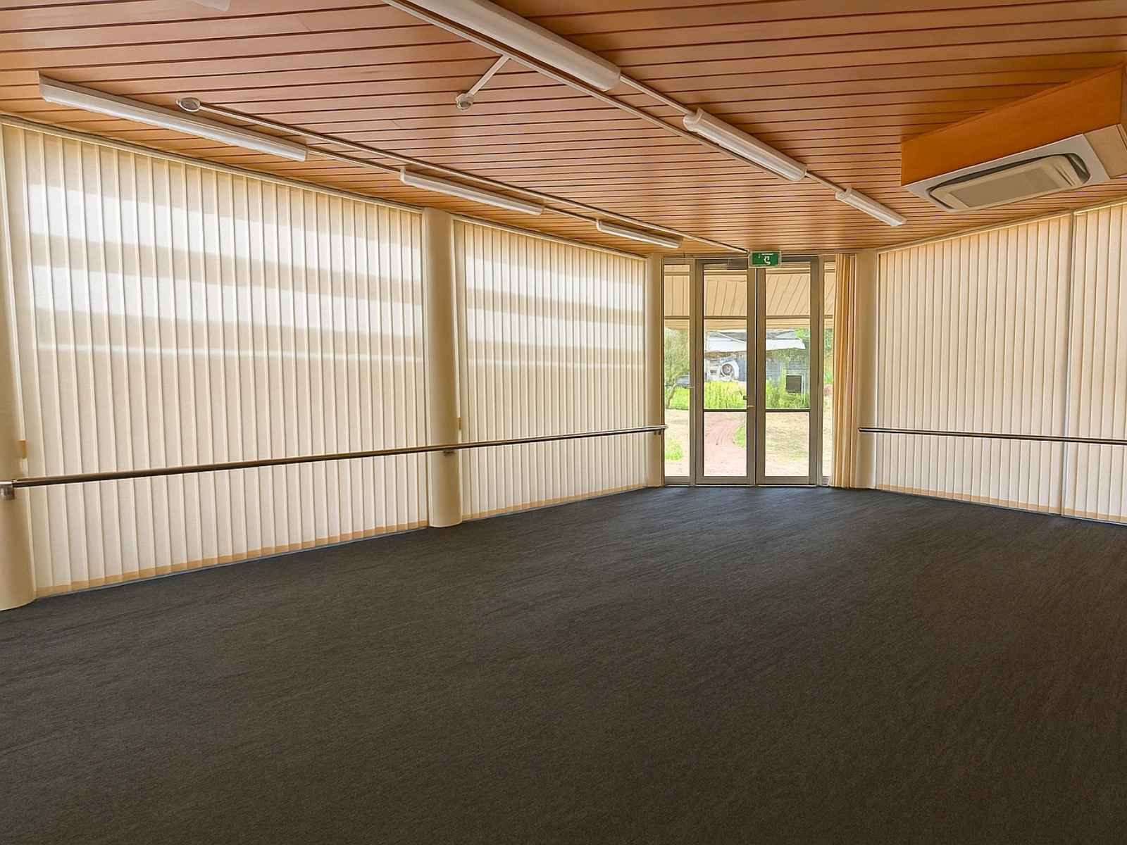 Light-filled side room with vertical blinds and timber ceiling.