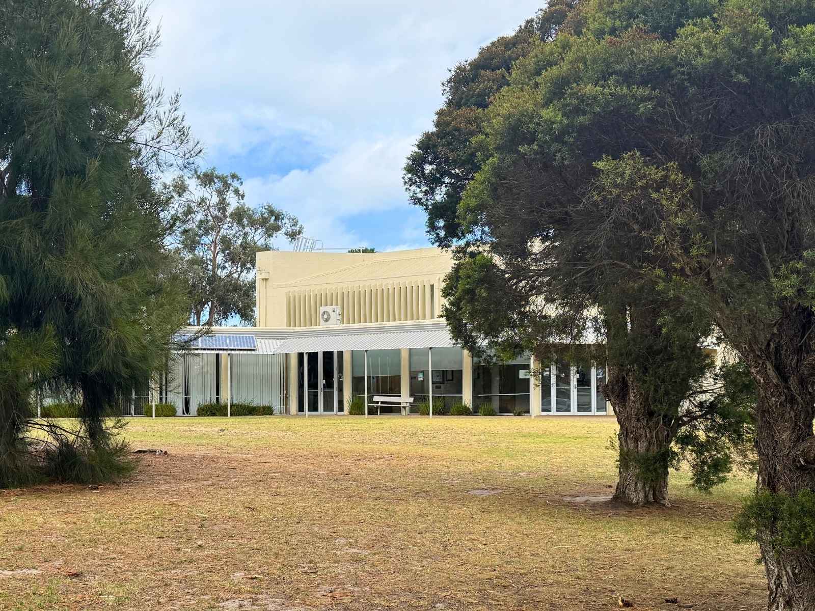 Side exterior shot of hall through surrounding trees.