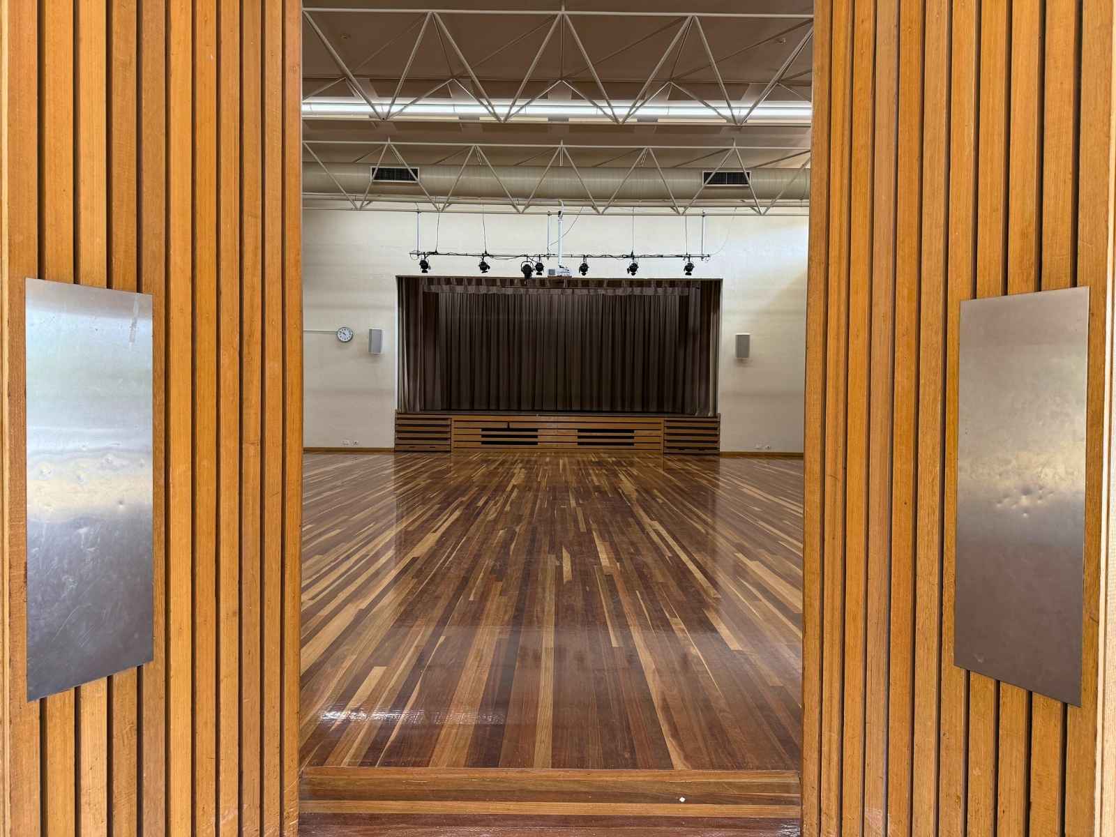 View from entry into hall, showing polished wooden floors and stage.