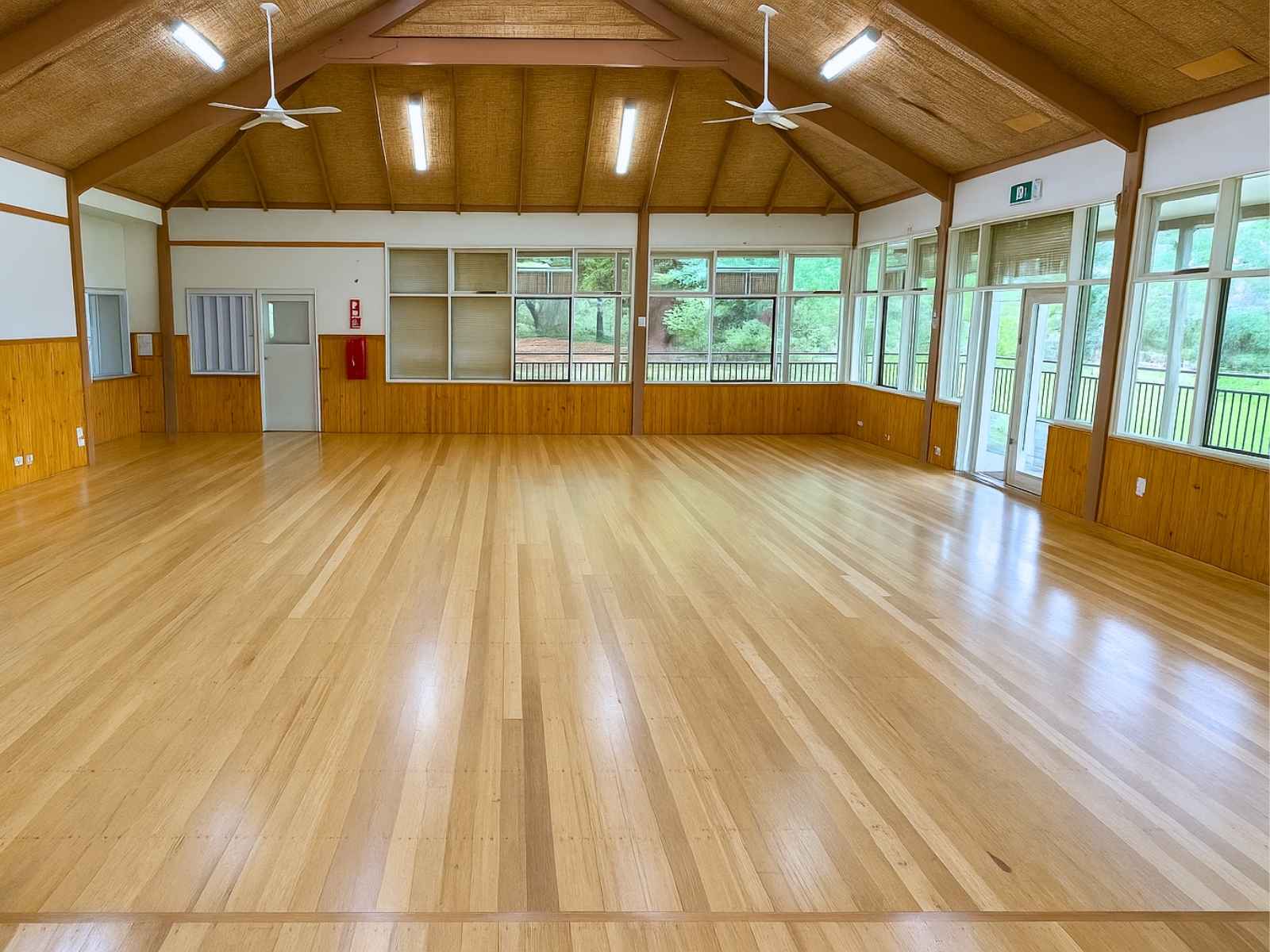 Spacious hall at Main Ridge Community Hall viewed from the opposite end, highlighting the ceiling fans, timber details, and light-filled windows.