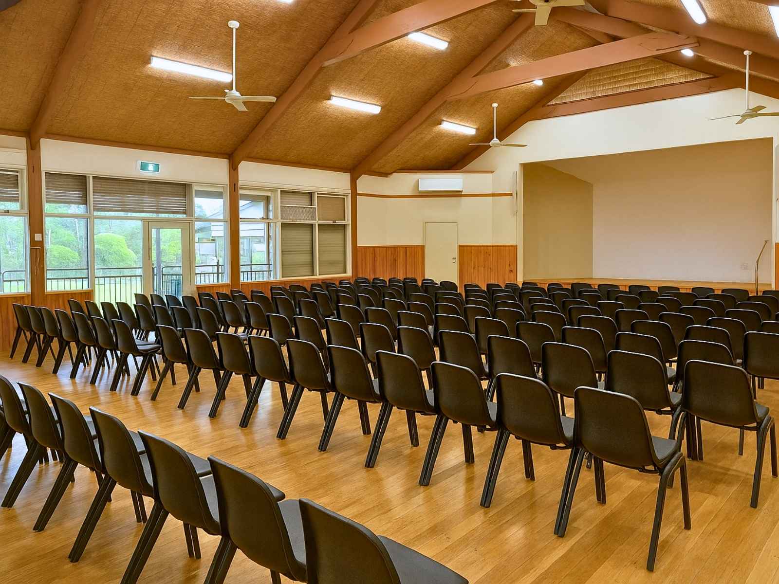 Wide-angle view of Main Ridge Community Hall interior showing timber floors, high ceilings, and rows of chairs arranged for an event.