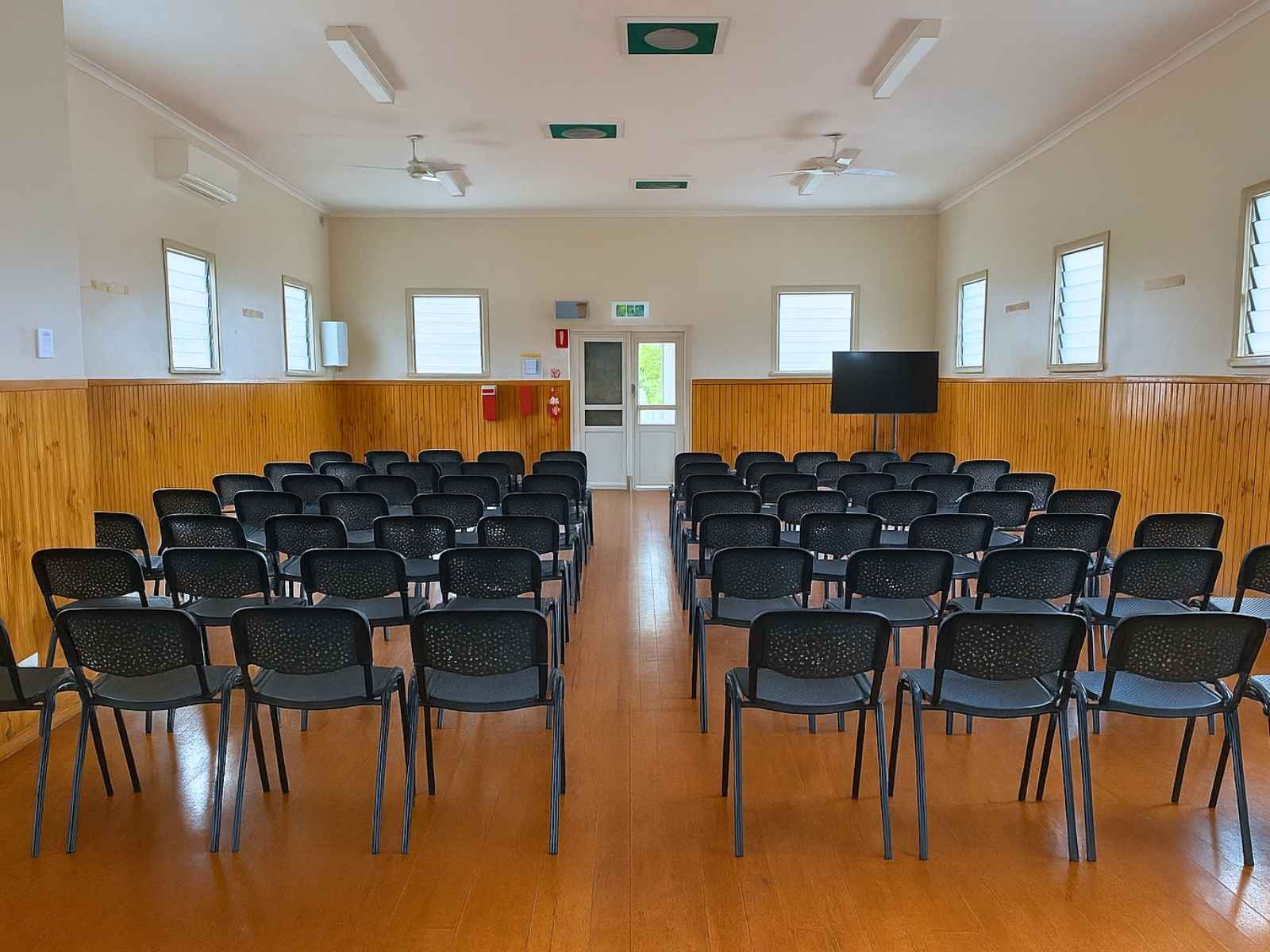 Interior of Bittern Hall set up with rows of black chairs facing a screen, ideal for gatherings or services.