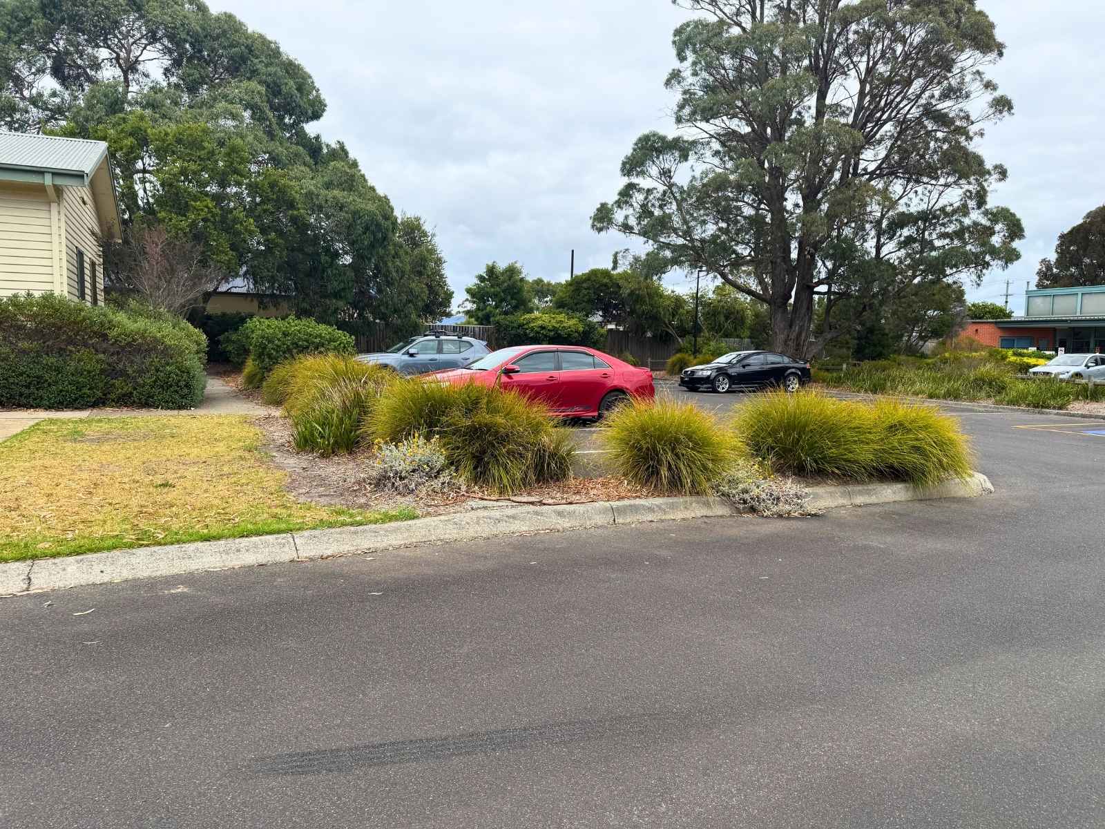 Car park area adjacent to Bittern Hall with several parked vehicles and landscaped garden beds.