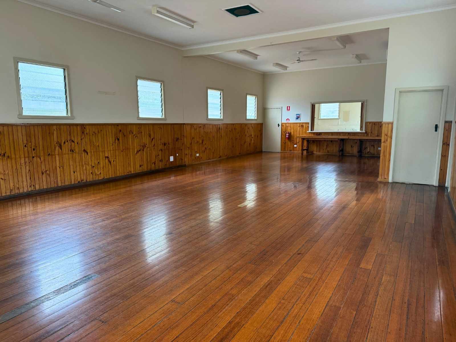 Open interior space inside Bittern Hall featuring polished wooden floors, timber panel walls, and a serving counter.