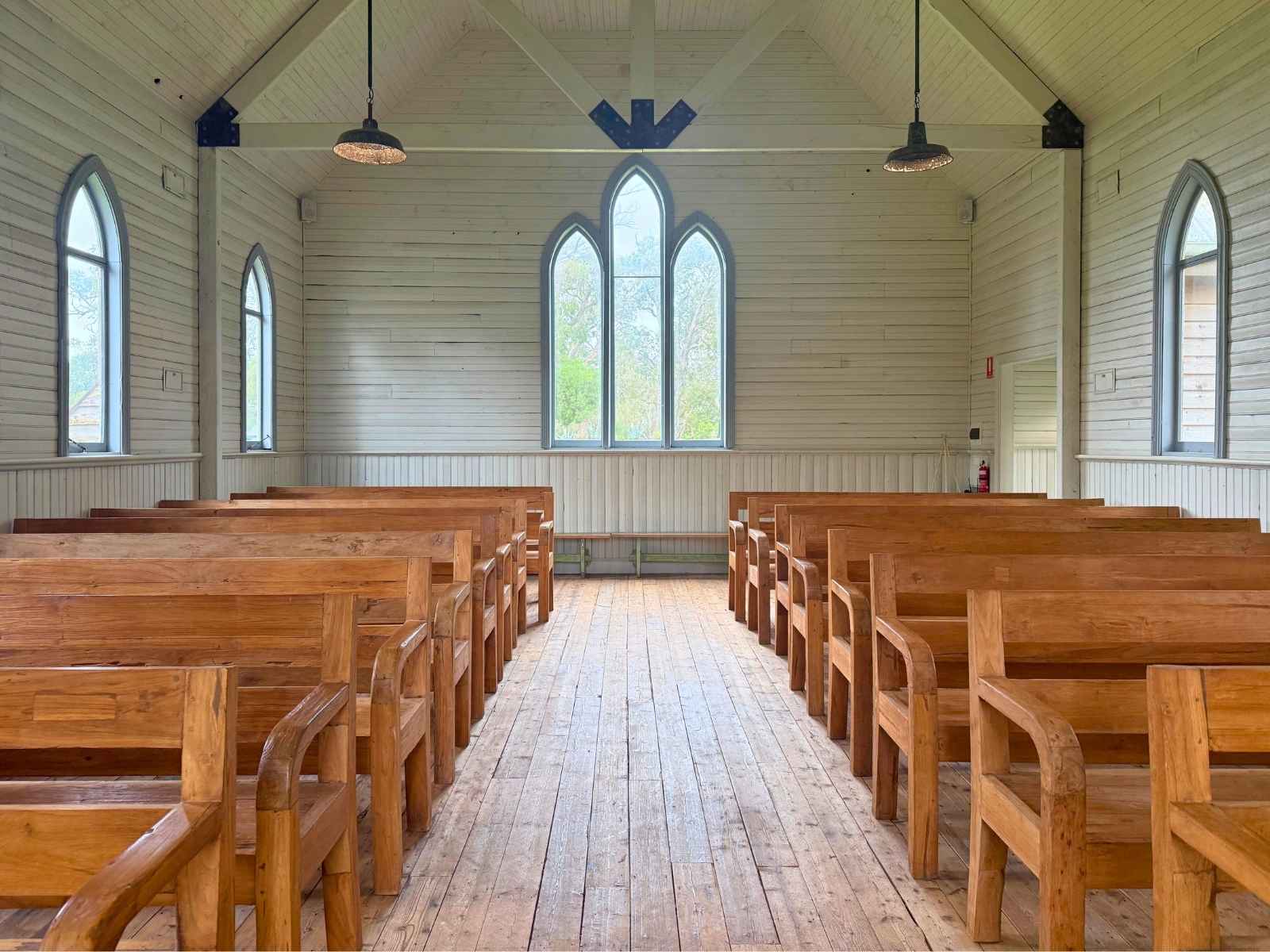 Tanglewood Estate inside the beautiful 100 year old chapel with custom wooden pews and beautiful high ceiling features. Light shining through curved windows. Looking to back of chapel.