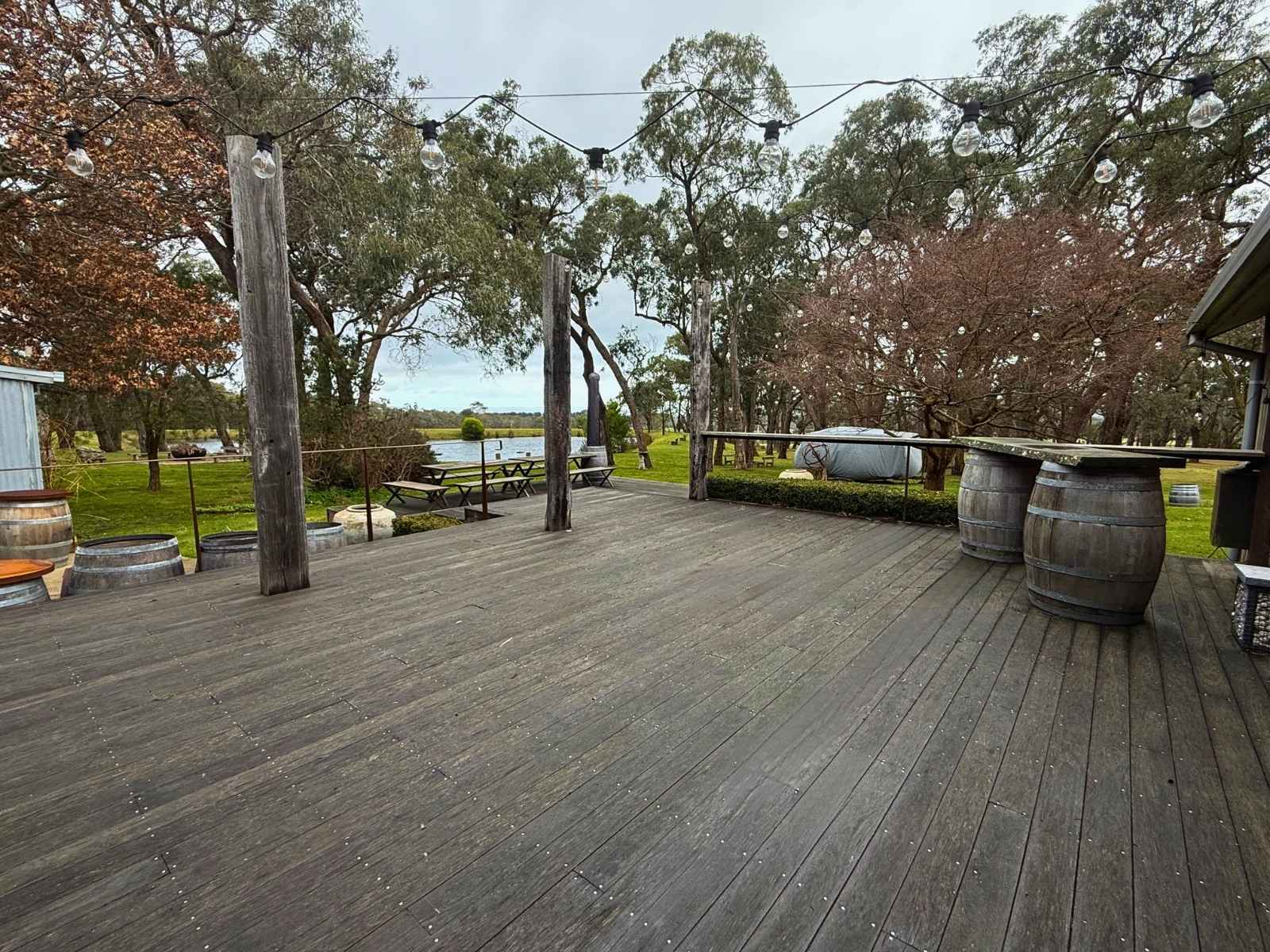 Deck space at The Winery at Tanglewood Estate in Dromana. Beautiful festoon lights hang above with views of the close dam and Port Phillip Bay views too.