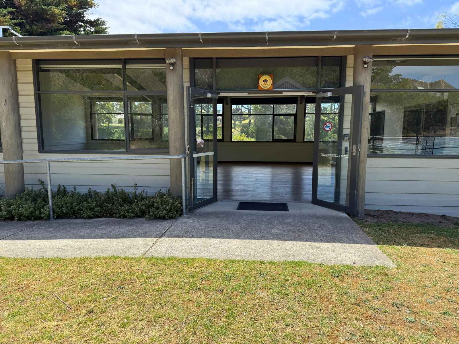 Front entrance of Watsons Pavilion with glass doors open and pathway leading to interior.