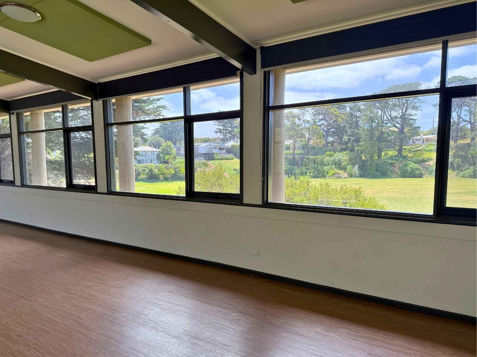 Unfurnished view of the indoor space with timber floor and expansive windows looking out to the grounds.