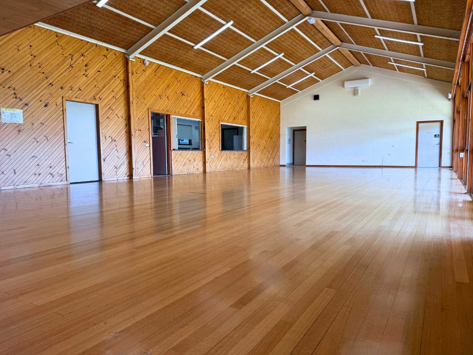 Wide shot of the wooden floor and kitchen servery area, ideal for flexible event setup.