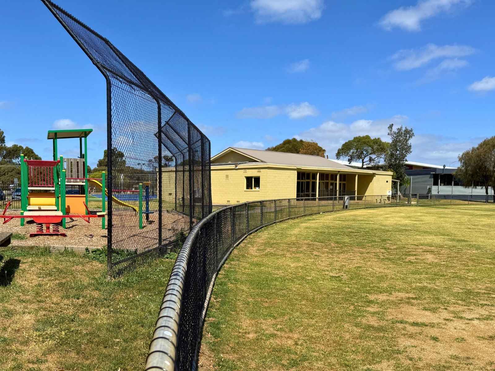 Children’s playground beside the hall, with the building and oval visible in the background.