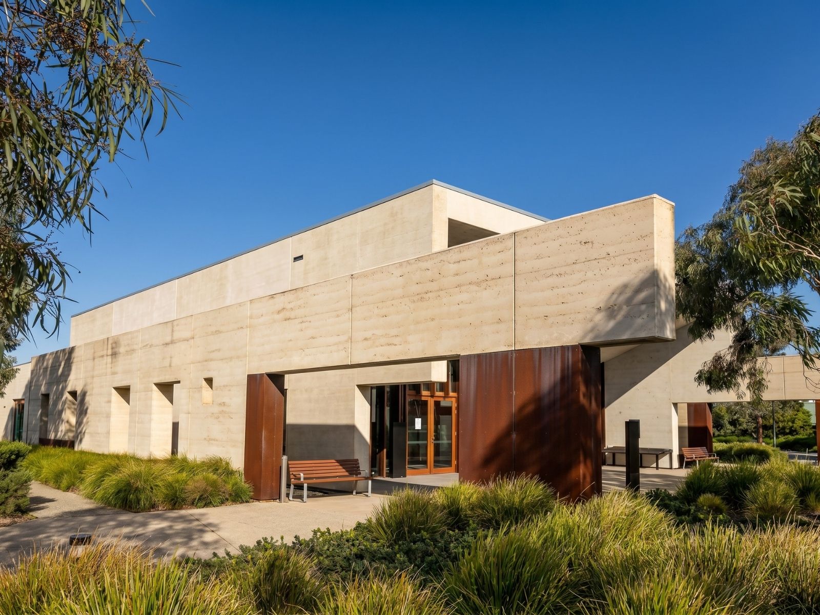 Entrance to Cirrus Chapel at Bunurong Memorial Park, Dandenong South, framed by rammed earth, Corten steel and native grasses