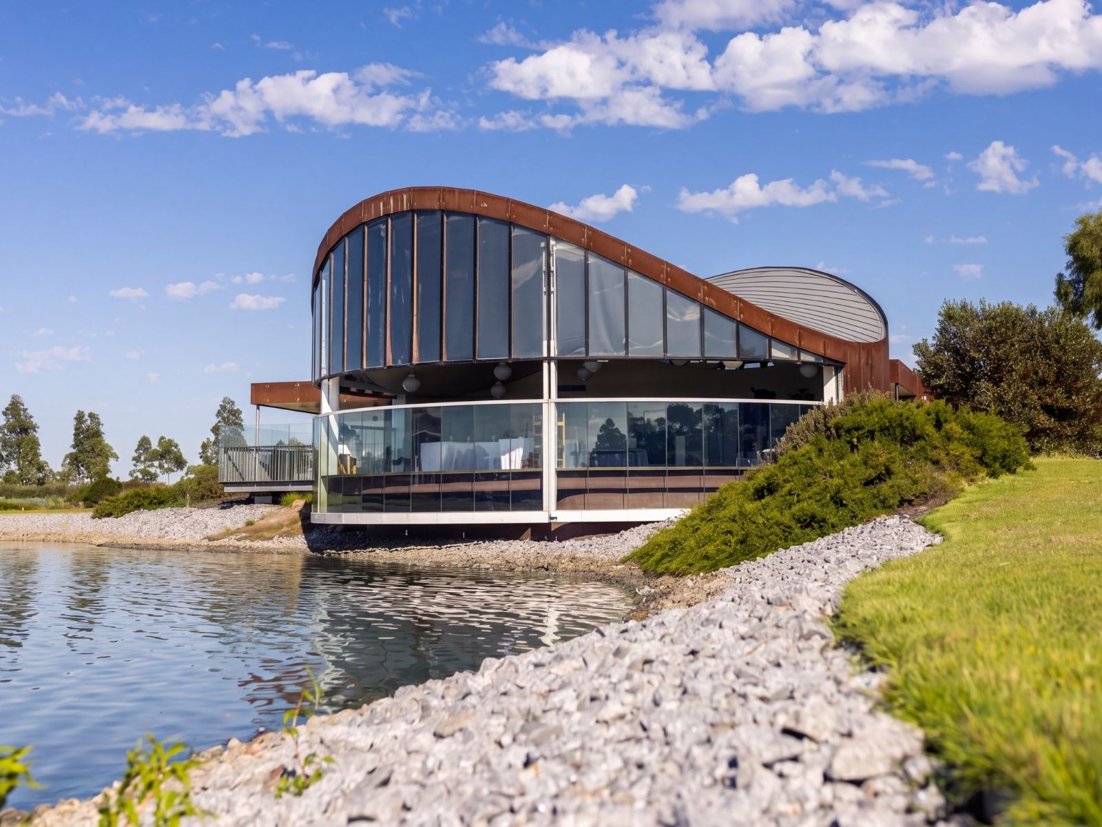 Exterior of Sanctuary Chapel at Bunurong Memorial Park with sweeping Corten roofline at the water's edge