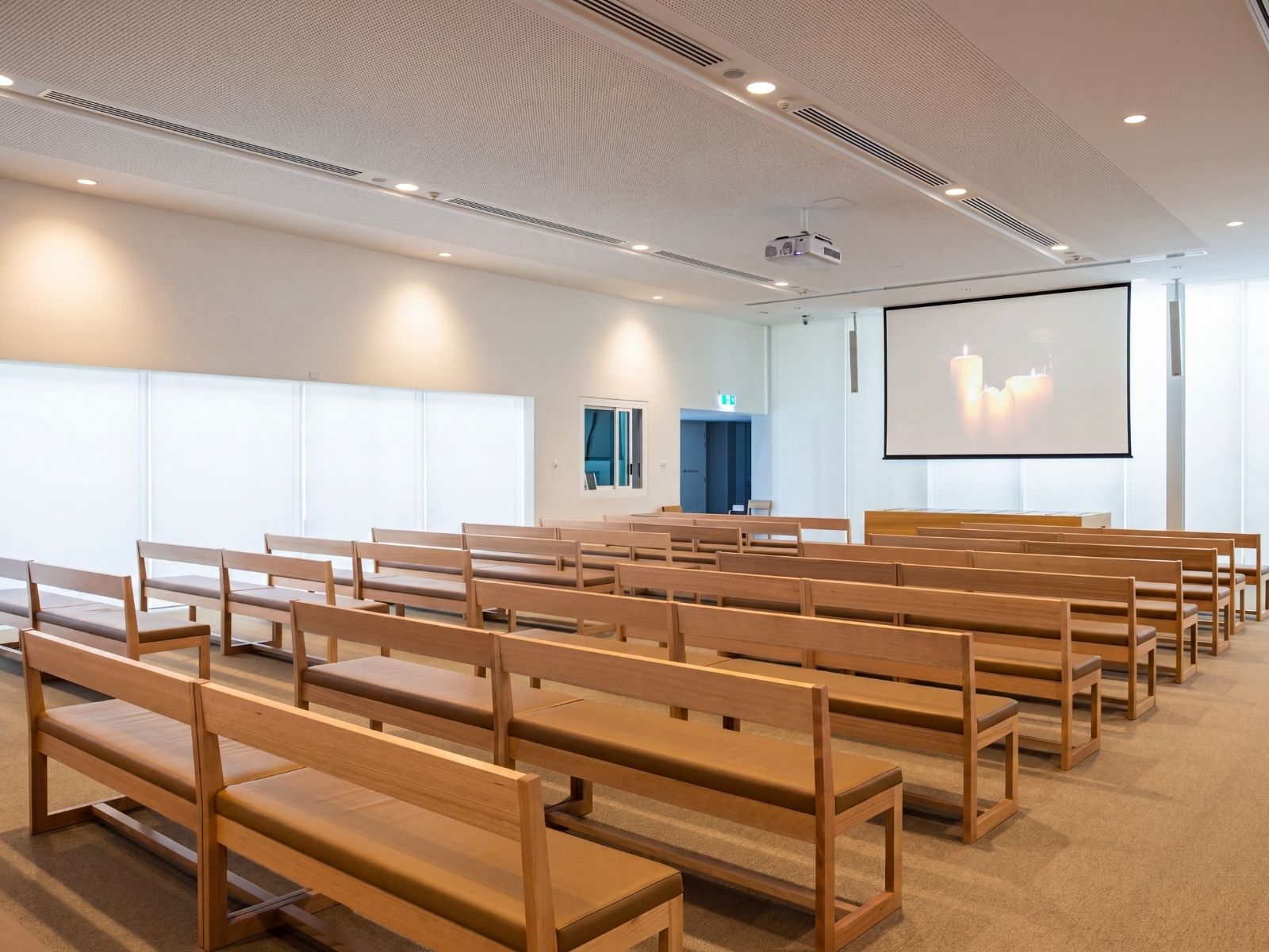 Cumulus Chapel interior at Bunurong Memorial Park with timber pews, projection screen and translucent windows