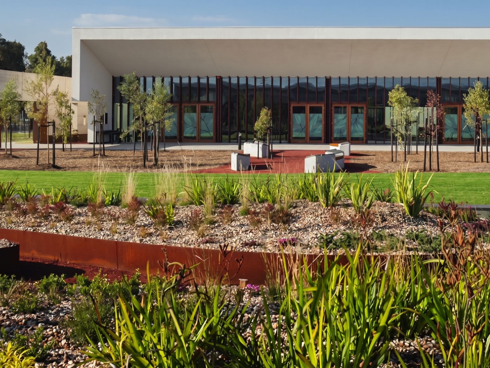 Native garden beds and red gravel courtyard outside Cumulus Chapel at Bunurong Memorial Park