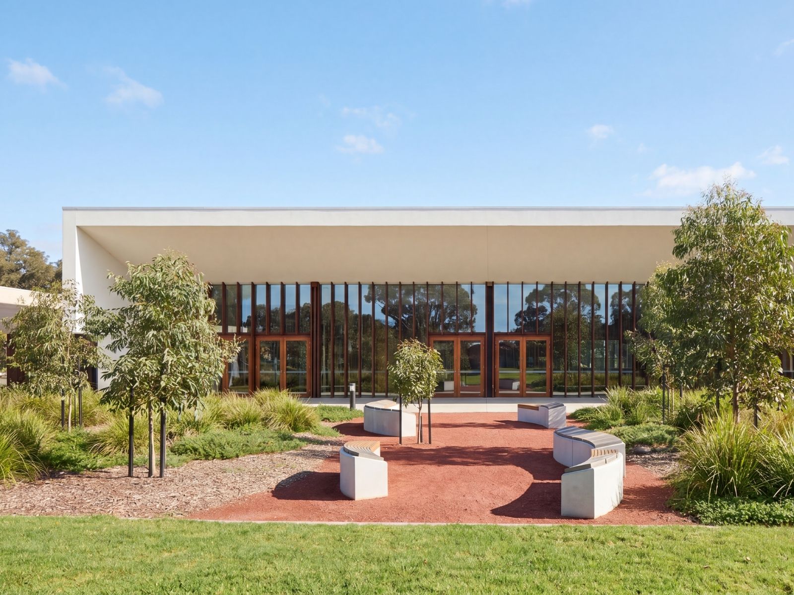 Exterior of Cumulus Chapel at Bunurong Memorial Park framed by established eucalypts and courtyard seating