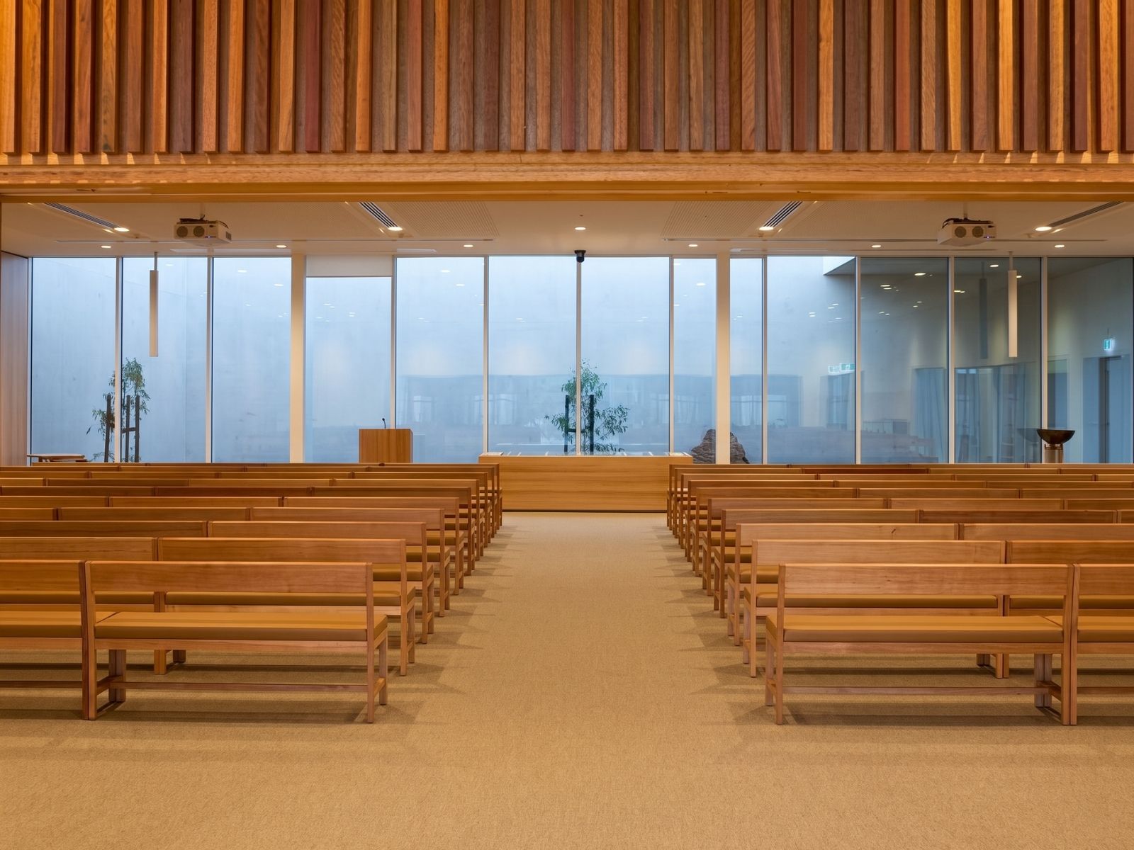 Central aisle of Stratus Chapel at Bunurong Memorial Park with timber pews and slatted timber feature wall