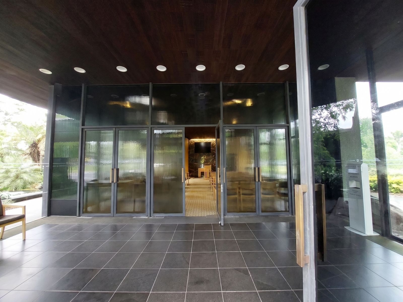 Covered entry porch at Blair Chapel Springvale, glazed doors opening to the chapel with garden reflections