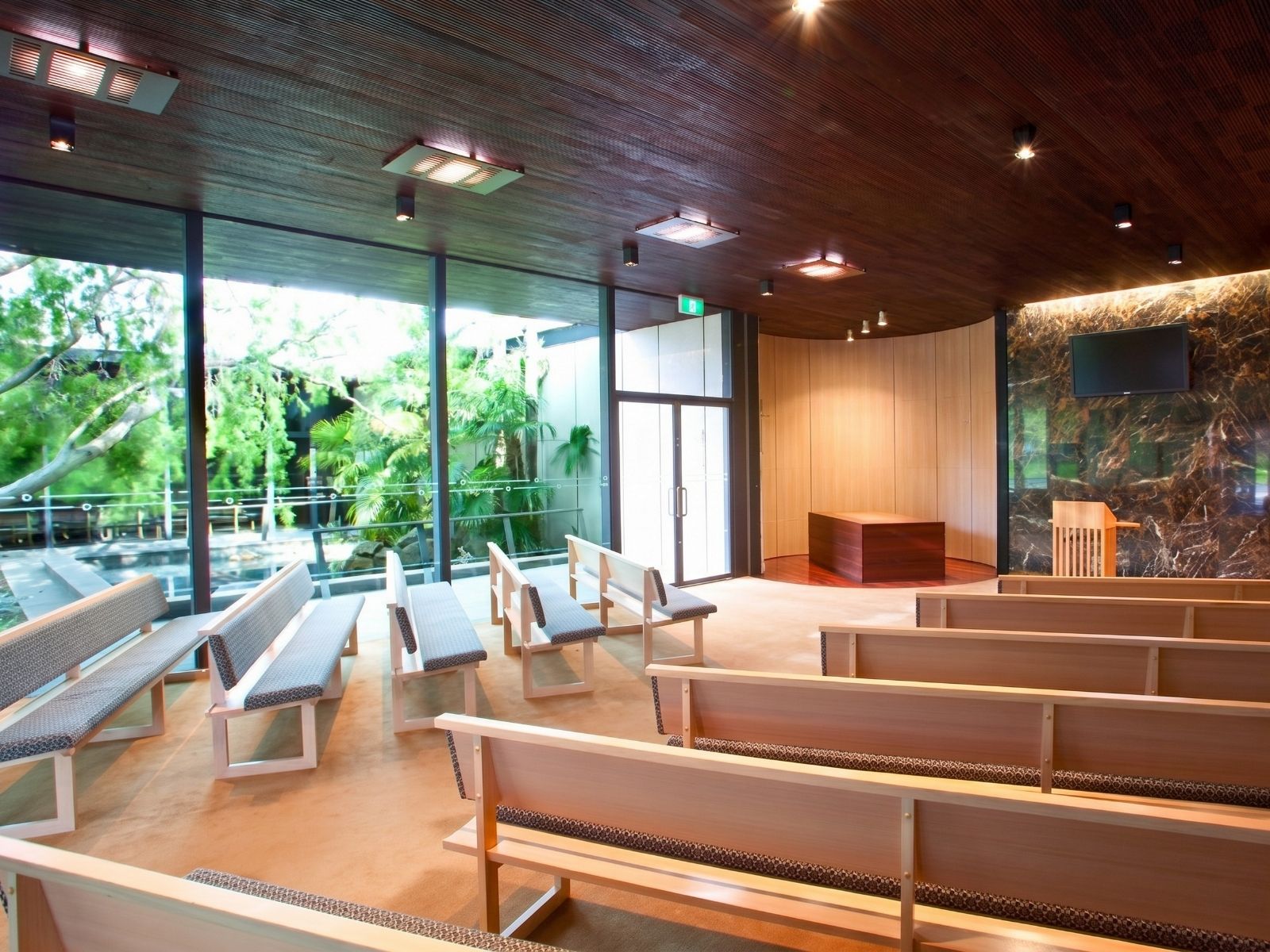 Blair Chapel interior with timber pews beside floor-to-ceiling windows overlooking the fern courtyard garden