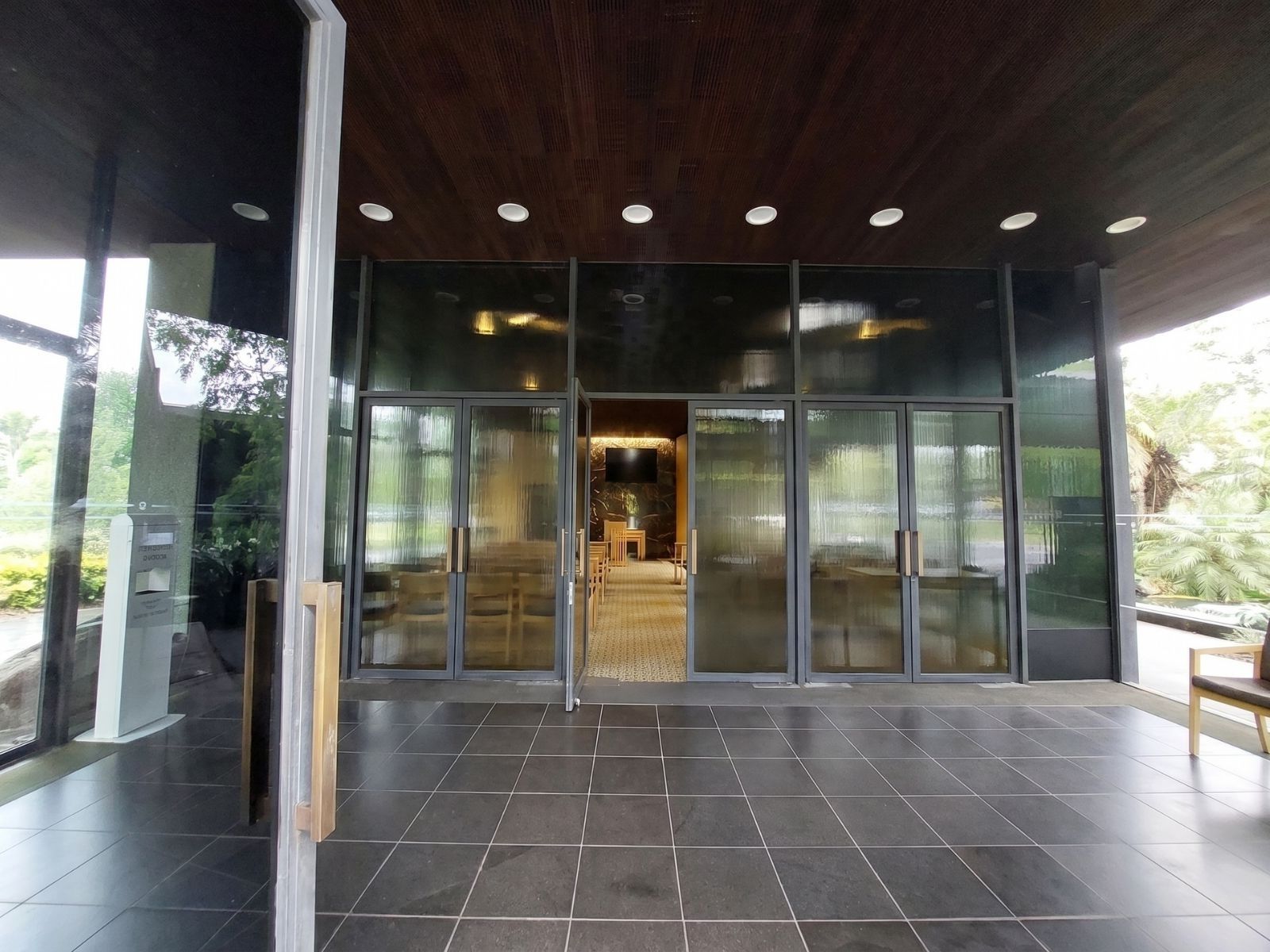 Covered entry porch at Wilson Chapel Springvale, glazed doors opening to the chapel with garden reflections