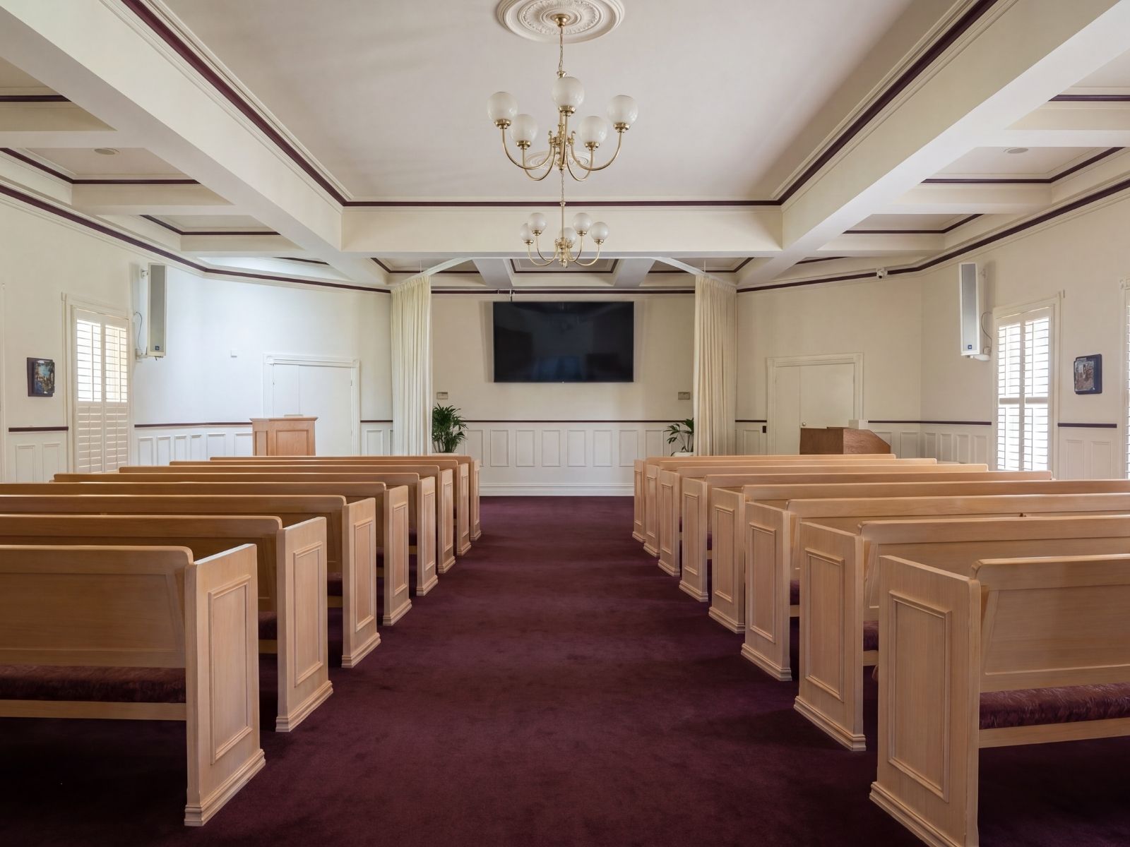 Timber pews lining the burgundy-carpeted aisle inside Federation Chapel at Lilydale
