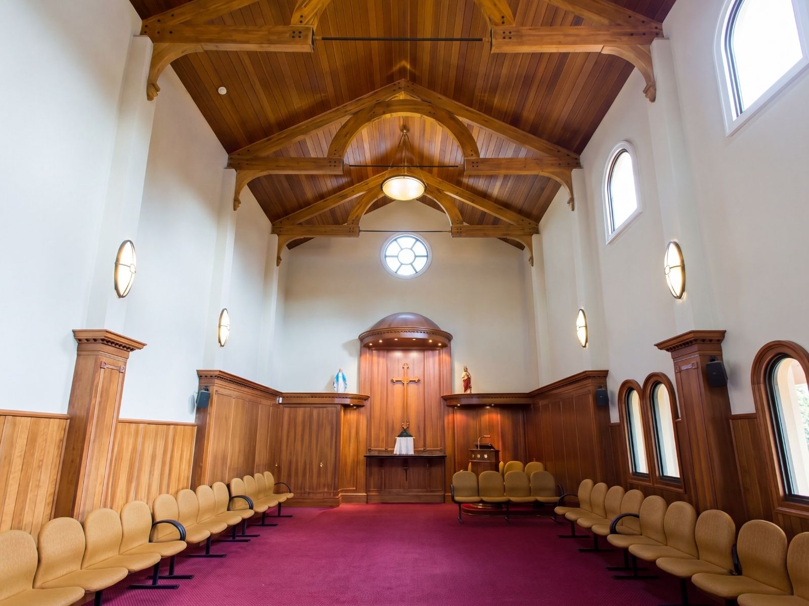 Timber-trussed chapel interior at Preston Cemetery with altar, cross and devotional statues