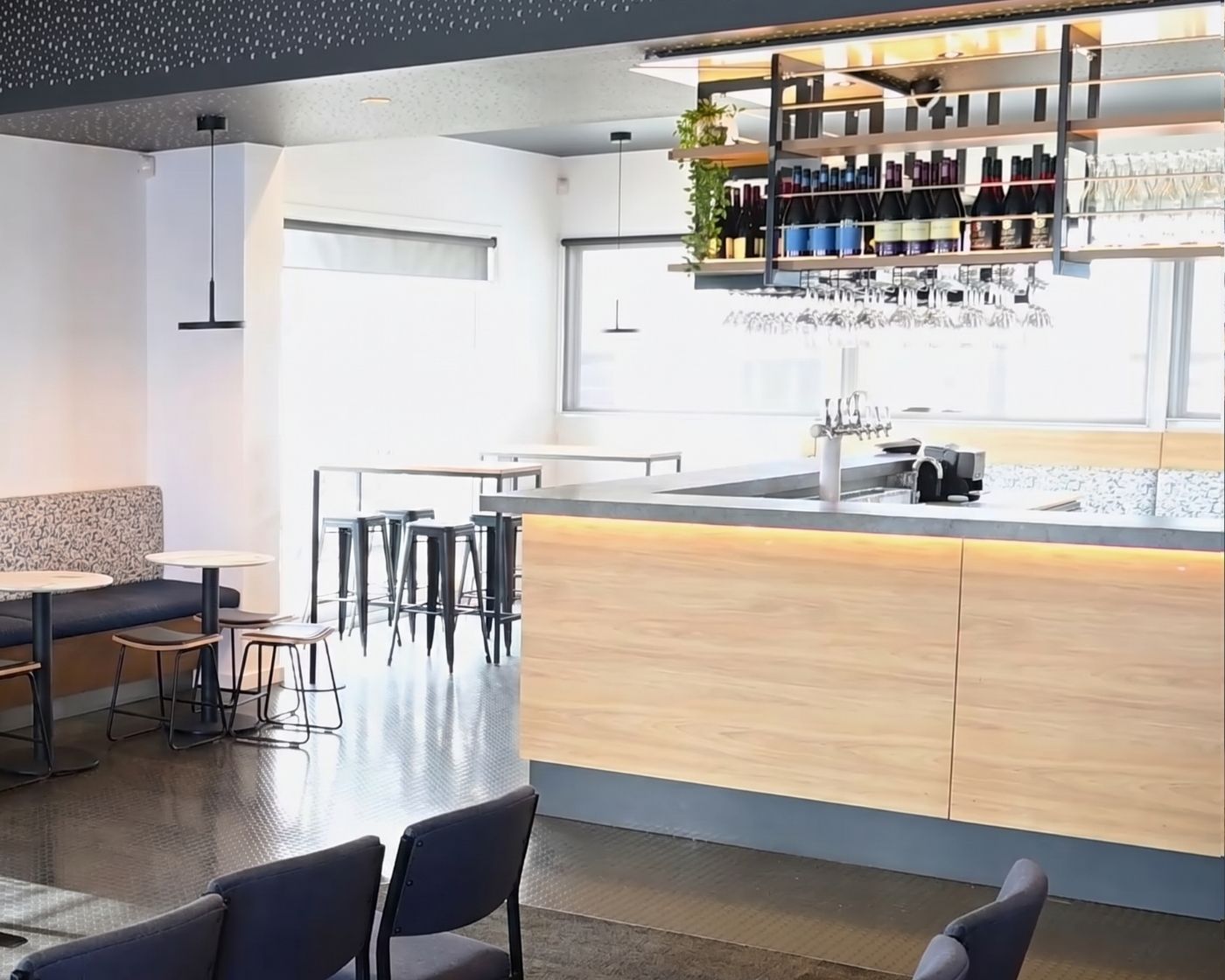 Clubhouse bar with timber counter, open shelving and banquette seating in a quiet corner
